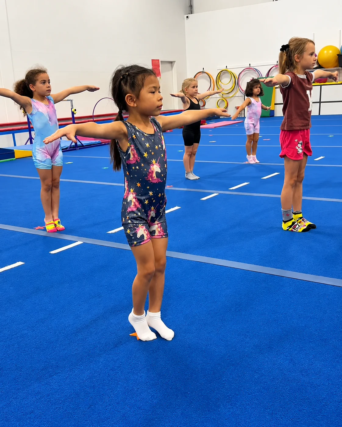 A Level 1 class at Rhythmic Art: five girls in a line with arms out on the blue floor