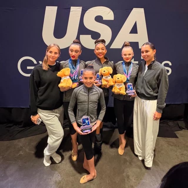Rhythmic Art gymnasts and coaches with their medals at a USA Gymnastics event