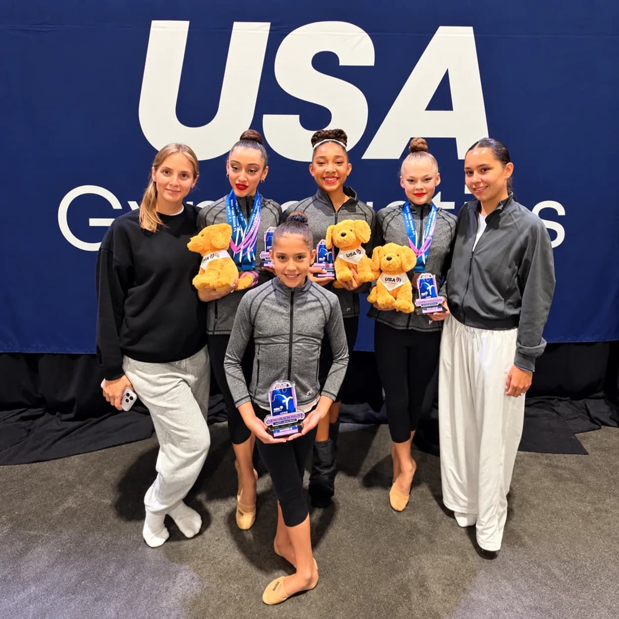 Rhythmic Art gymnasts and coaches with their medals at a USA Gymnastics event