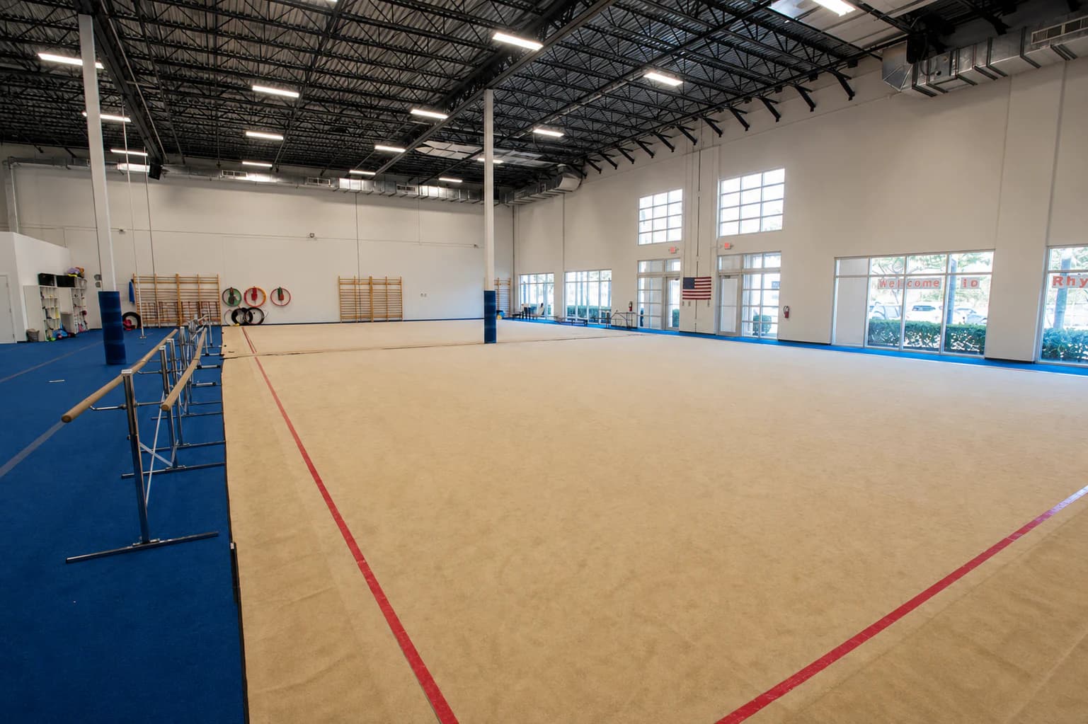 The empty training floor at Rhythmic Art, with ballet barres and wall bars waiting along its edges