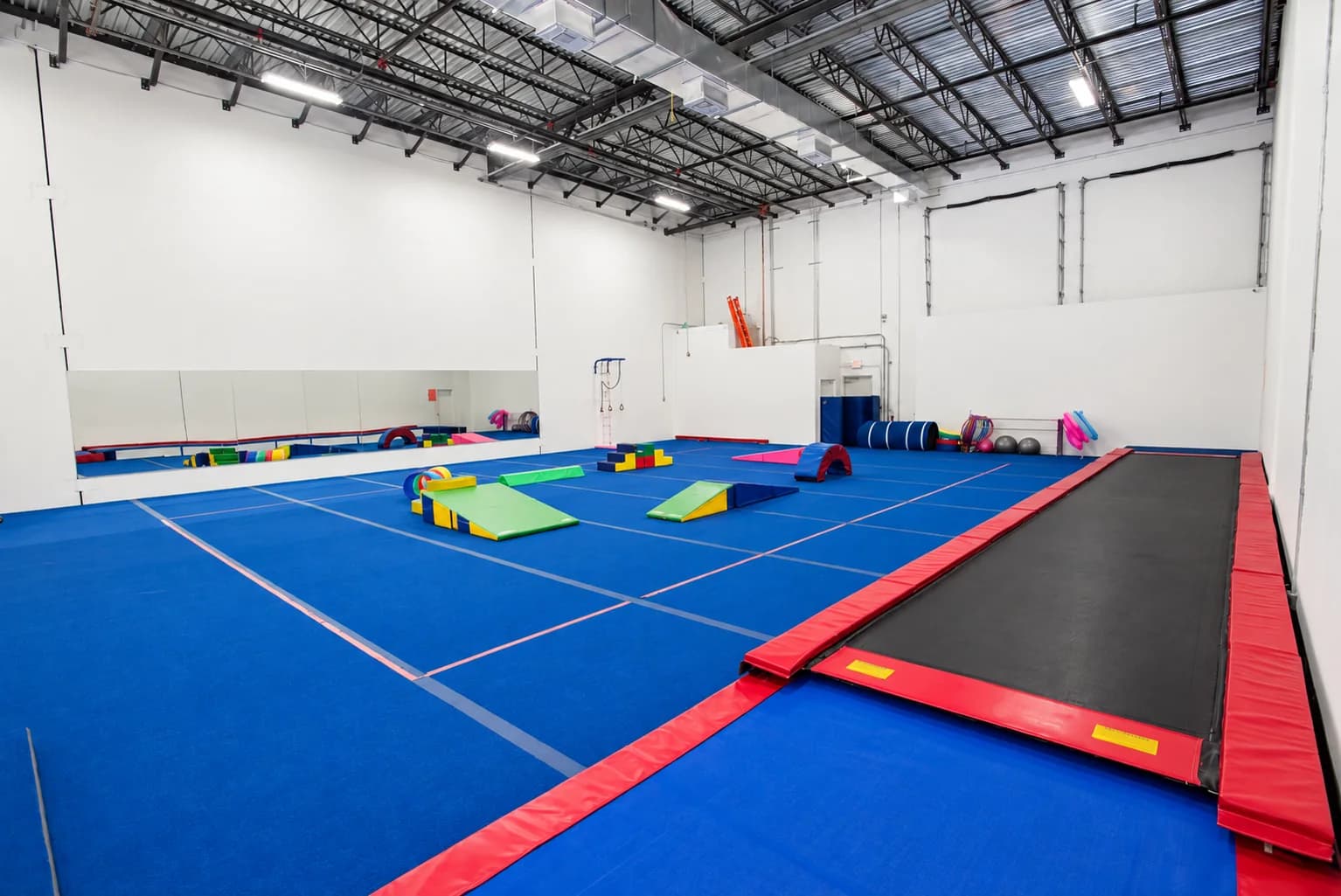 Gymnastics equipment arranged on a blue training floor at Rhythmic Art