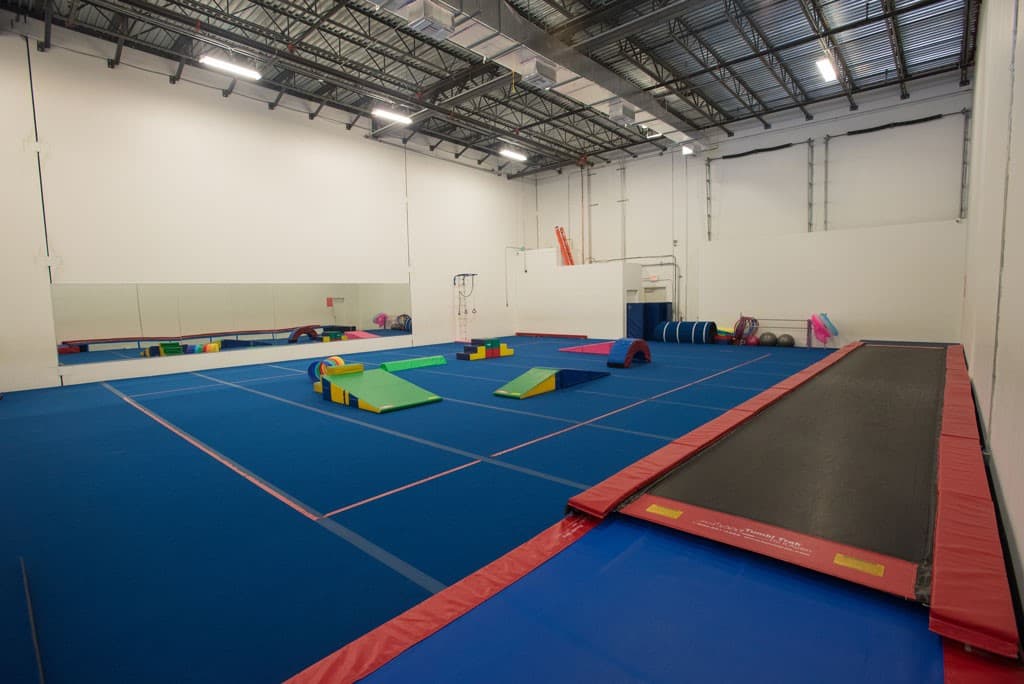 Gymnastics equipment arranged on a blue training floor at Rhythmic Art