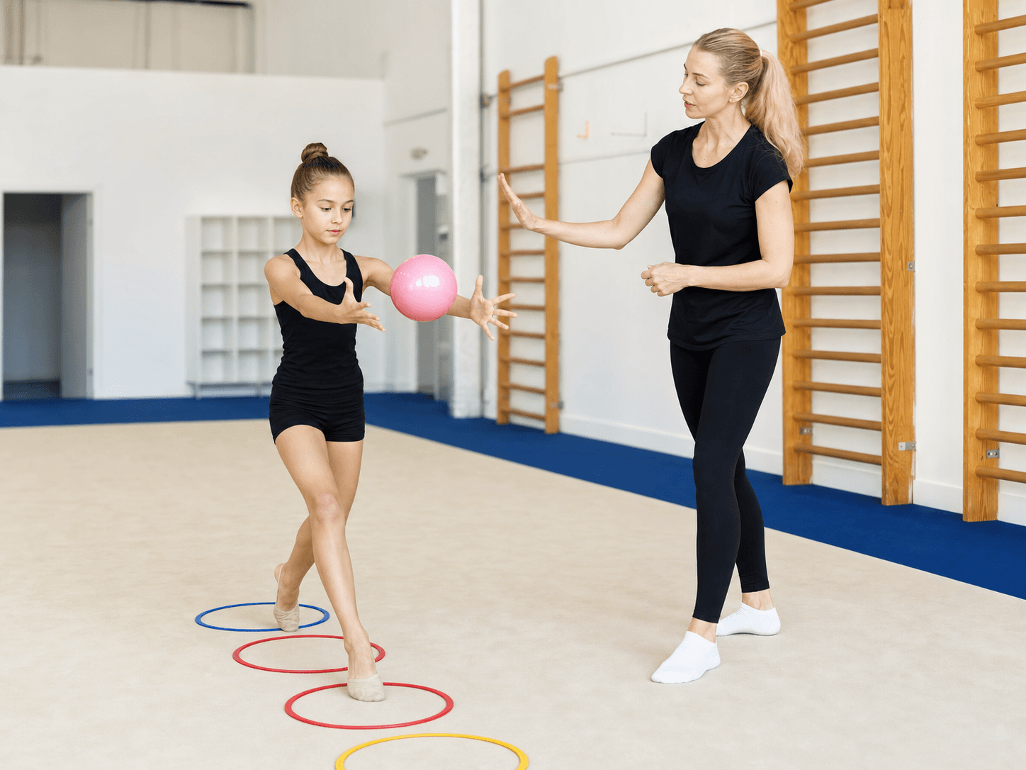 Coach helping an athlete practice coordination with a ball and floor markers